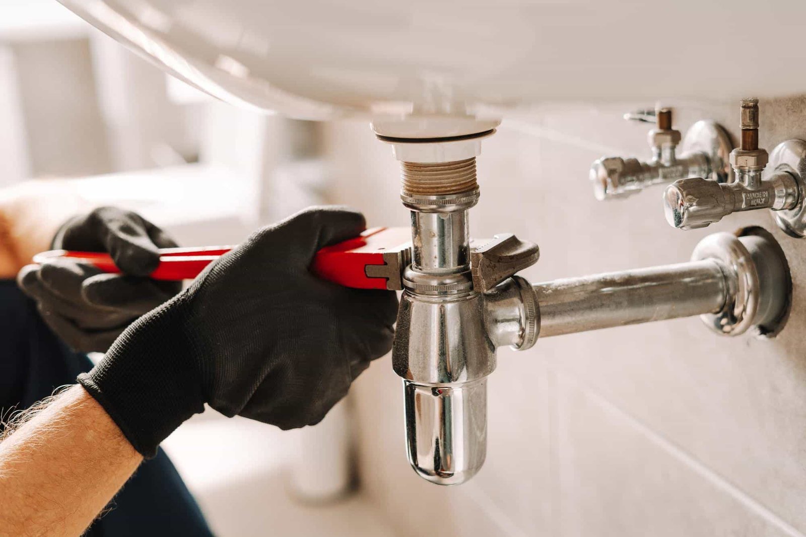 Plombier intervenant sous lavabo pour réparation à Amiens